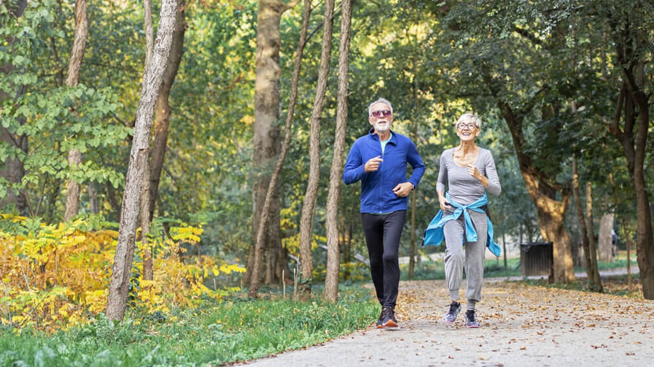 Older couple running on path in the woods