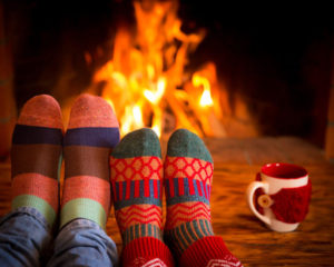 Couple relaxing at home. Feet in Christmas socks near fireplace. Winter holiday concept