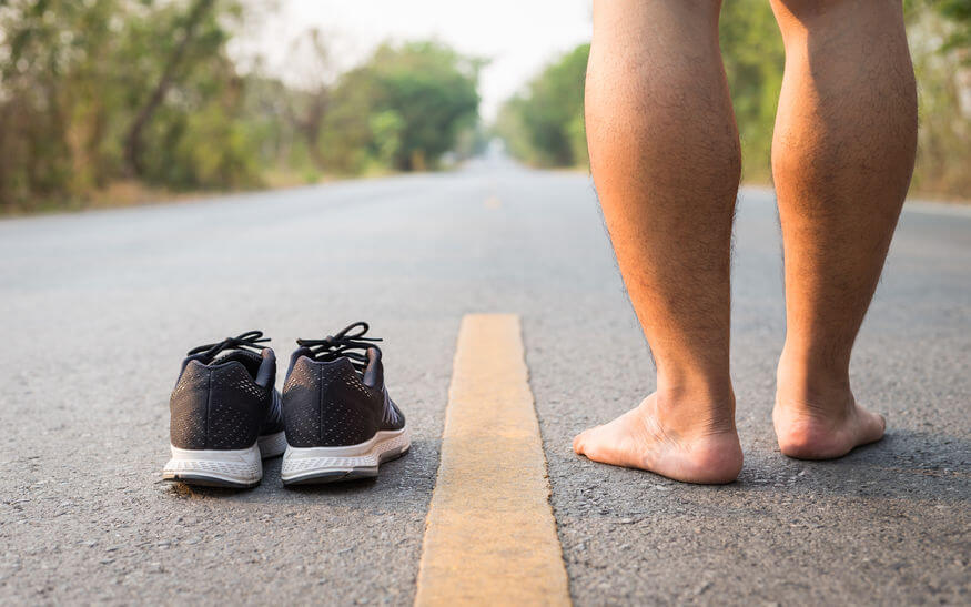 Close up legs of man with black running shoes on asphalt road in morning time